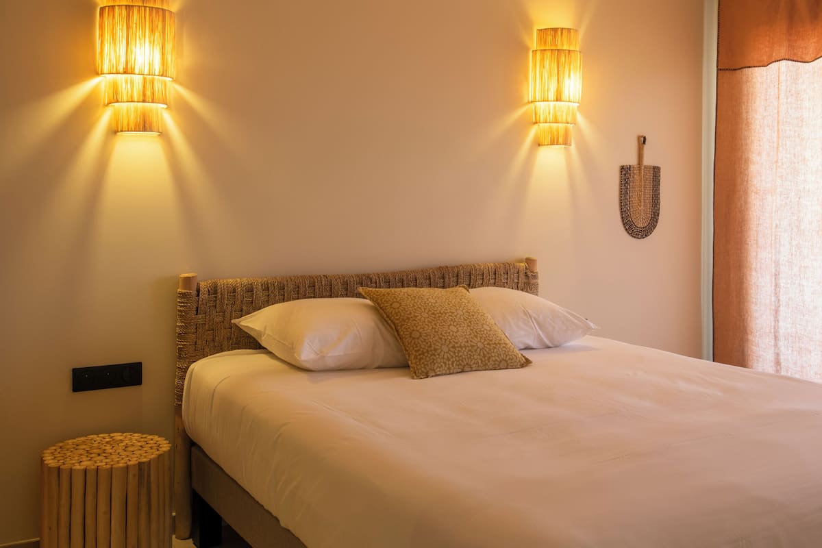 Ein Schlafzimmer mit einem Bett, zwei Wandlampen, einem kleinen runden Tisch und einem Wanddekor.