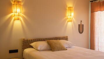 A bedroom with a bed, two wall-mounted lamps, a small round table, and a wall-mounted decorative item.
