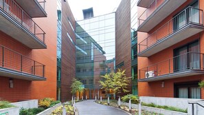 A modern building with a central glass facade, red brick walls, and balconies with metal railings. - Apartamenty Sun & Snow Angel City Kraków (Kraków)
