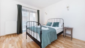 Un dormitorio con una cama, una mesita de noche, una lámpara y una ventana con cortinas.