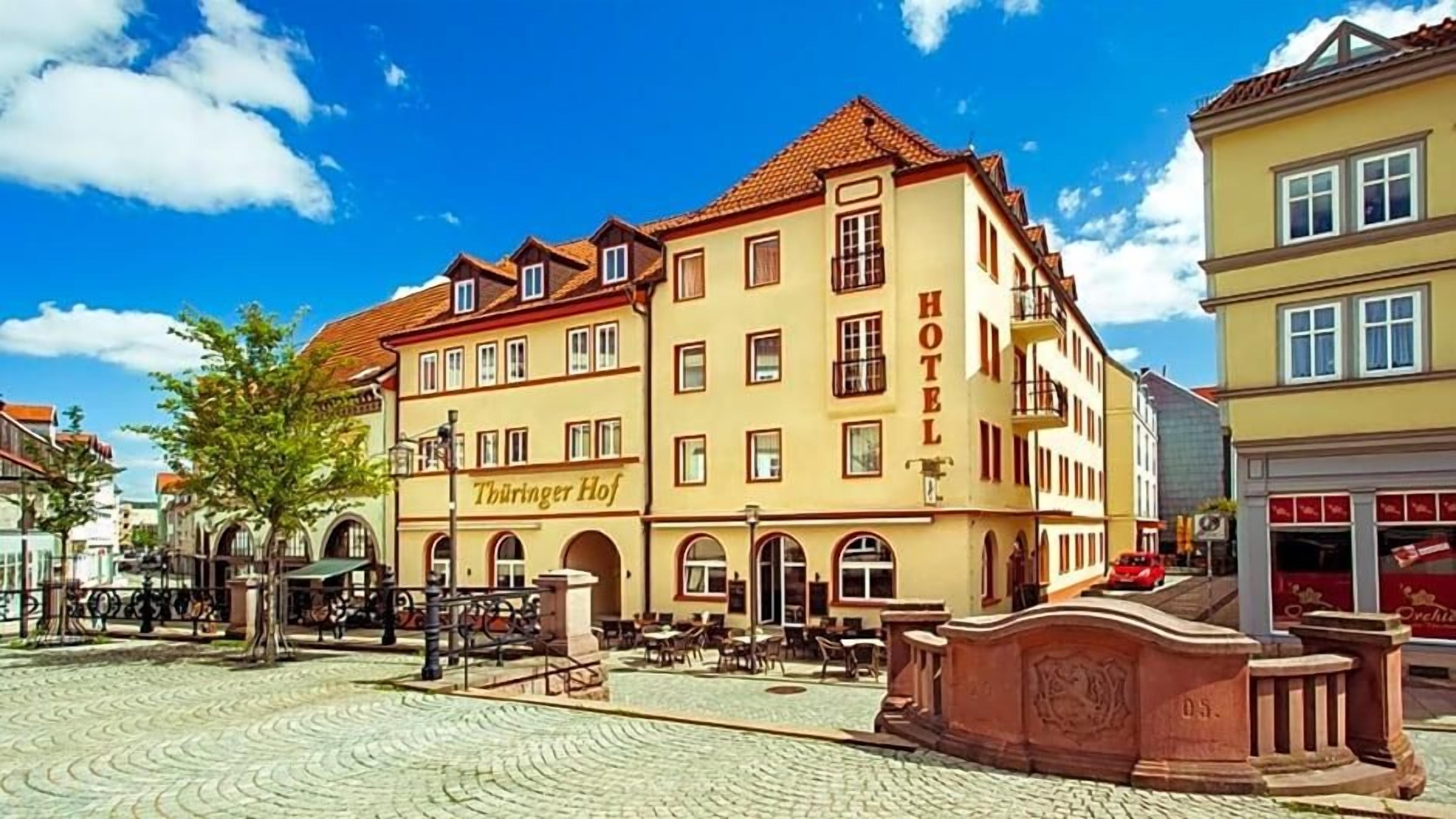 A hotel with a sign reading 'Hotel Thuringer Hof' in a European town square.