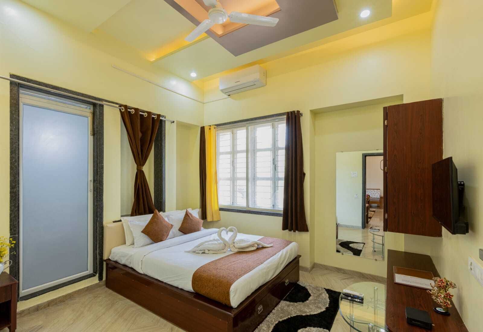 A hotel room with a bed, a desk, a chair, a TV, and a window.