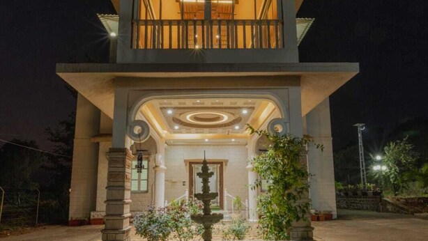 Edificio de dos pisos con un patio central, una fuente y un balcón con iluminación.