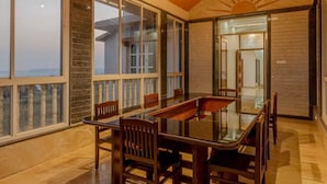 Una habitación amplia con techo alto, ventanas grandes y una zona de comedor con mesa y sillas.