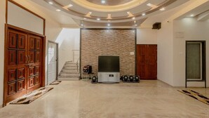 Amplia sala de estar con pared de piedra, televisor de pantalla plana y escalera que conduce a un piso superior.