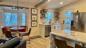 A modern kitchen with wooden walls, a stainless steel refrigerator, and a dining area with a marble island and leather chairs. - Sundance Carriage House, Romantic, Sleeps 5 (Sundance)