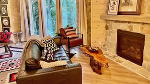 A cozy living room with a leather sofa, a wooden coffee table, and a stone fireplace. - Sundance Carriage House, Romantic, Sleeps 5 (Sundance)