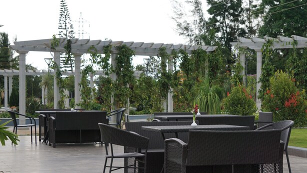 Ein Terrassenbereich im Freien mit Korbmöbeln und einer Pergola.