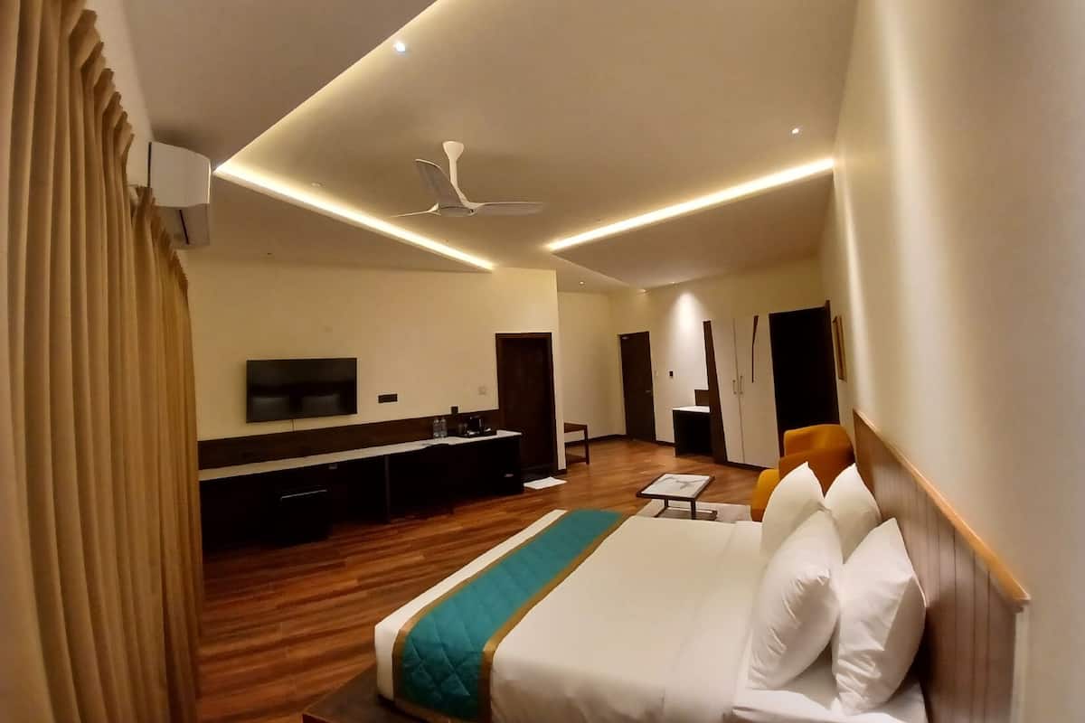 A modern hotel room with a large bed, a desk, a flat-screen TV, and a ceiling fan.