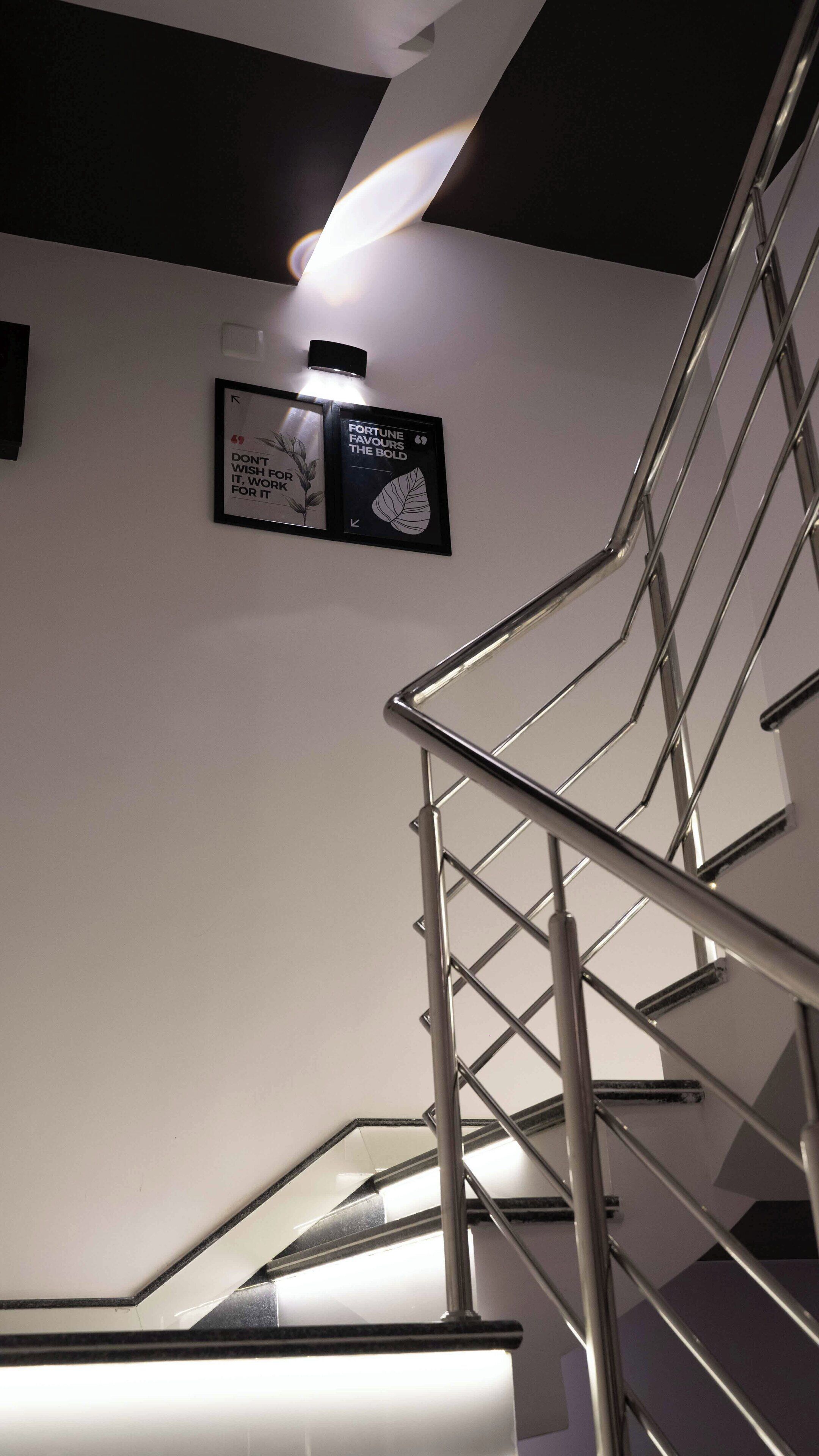 A staircase with a metal handrail and a wall-mounted sign with motivational quotes.