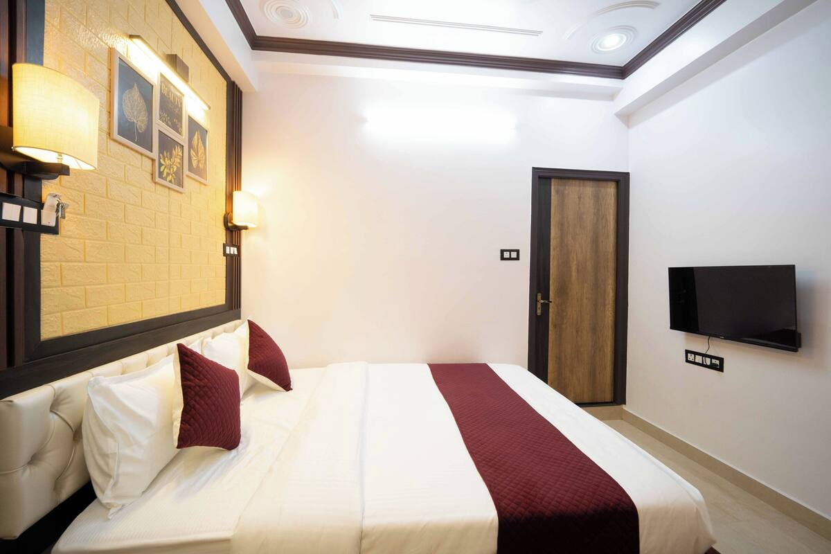 Quarto de hotel com uma cama, televisão e porta.
