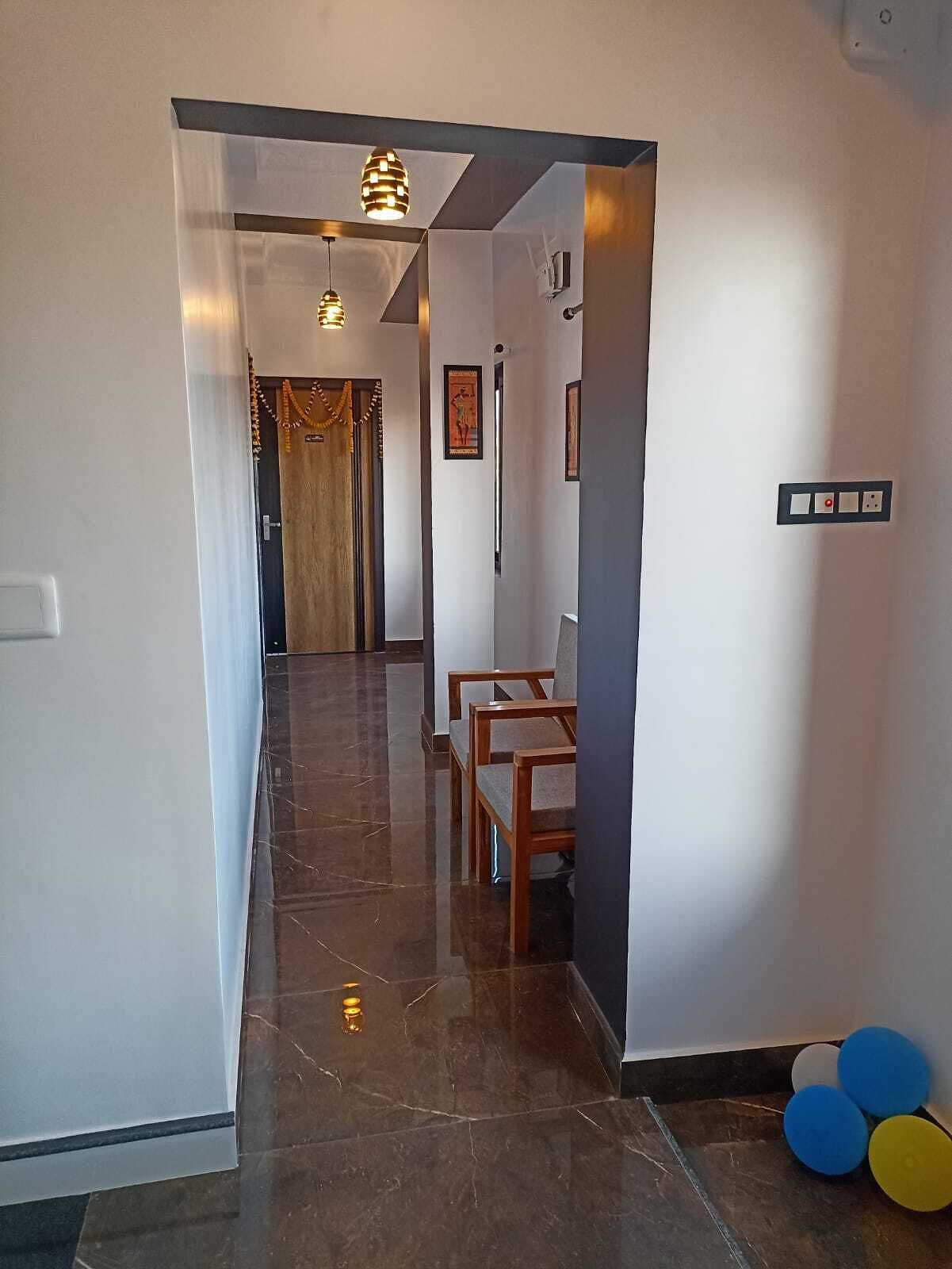 Un couloir avec une porte en bois, un tableau encadré et un interrupteur sur le mur.