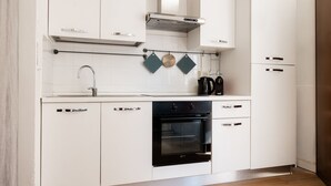 Una cucina moderna con mobili bianchi, un forno nero e una cappa aspirante in acciaio inossidabile.