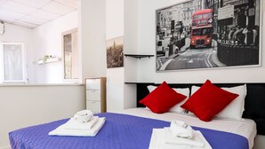 Una camera d'albergo con un letto grande, due cuscini rossi e una foto con vista sulla città.