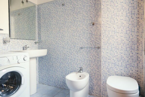 Un baño con lavadora, bidé e inodoro.