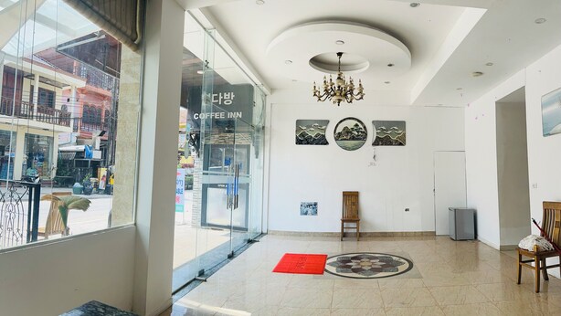 Interior de una cafetería moderna con un amplio ventanal, una araña y obras de arte en las paredes.