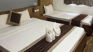 Habitación de hotel con dos camas, cabecero de madera, unidad de aire acondicionado y ventana con cortina.