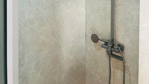 Ducha con cabezal de ducha manual y otro fijo en la pared.
