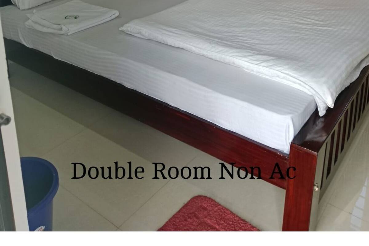 Una habitación doble con cama de madera, ropa de cama blanca y cortinas anaranjadas.