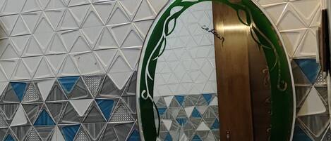 A bathroom with a white sink, a mirror with a green frame, and a patterned tile wall.