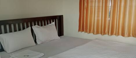 A double room with a wooden bed, white bedding, and orange curtains.