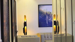 Een hotelkamer met een stadsgezichtschilderij aan de muur, een bank en een staande lamp.