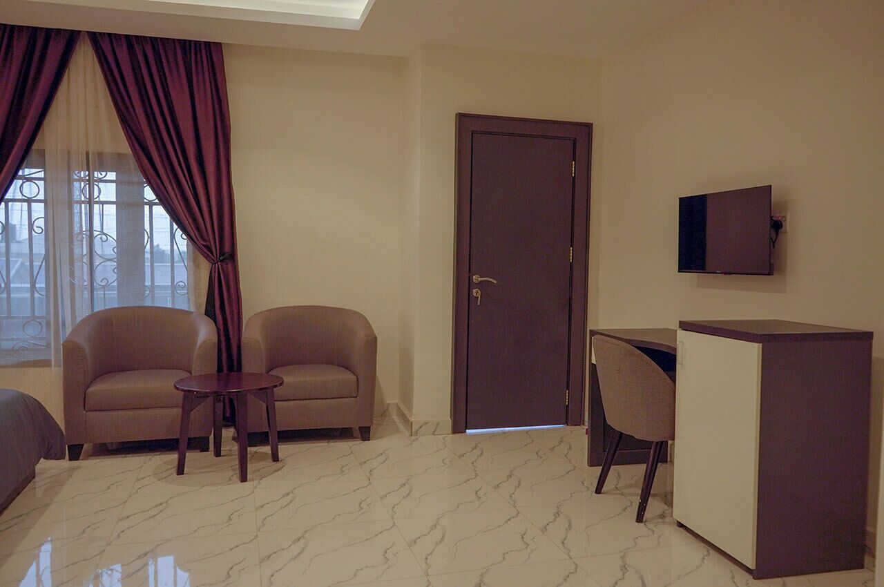 A room with two sofas, a small table, a cabinet, and a door.