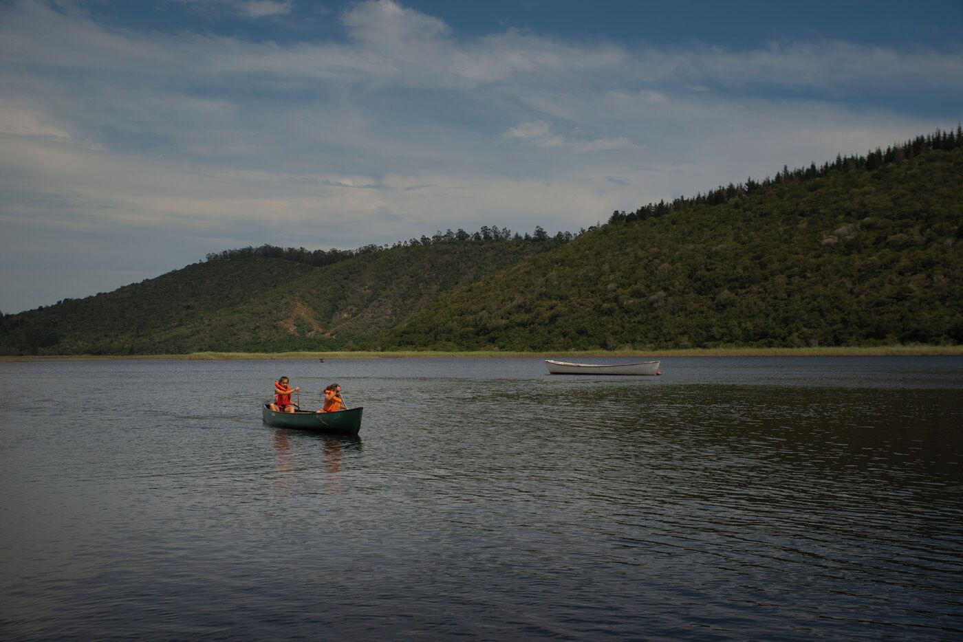 Un lago tranquilo con un bote llevando a dos personas.