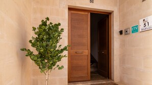 A potted plant in front of a wooden door with a number plaque.