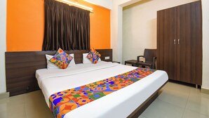 A hotel room with a bed, a nightstand, a chair, and a wardrobe. - DE COMFORT EXECUTIVE (Paud)