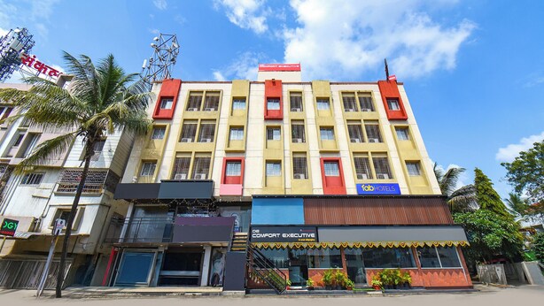 A multi-story building with a prominent red and yellow facade, featuring a sign for 'Comfort Executive' and 'Fab Hotels'. - DE COMFORT EXECUTIVE (Paud)