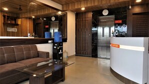 A reception area with a sofa, a glass table, and a reception desk. - DE COMFORT EXECUTIVE (Paud)