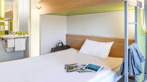 A bunk bed with a wooden headboard, a bedside table with a lamp, a mirror, and a green wall. - B&B Hotel Köln-porz (Cologne)