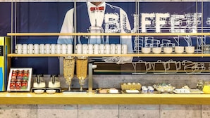 A buffet counter with a variety of food items, including fruits, pastries, and beverages. - B&B Hotel Köln-porz (Cologne)