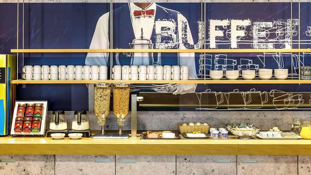 A buffet counter with a variety of food items, including fruits, pastries, and beverages. - B&B Hotel Köln-porz (Cologne)