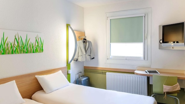 A hotel room with two beds, a desk with a computer, a TV, and a window with a view. - B&B Hotel Köln-porz (Cologne)