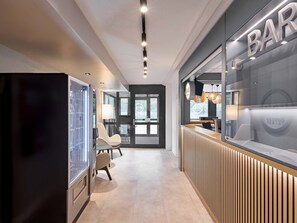 Ein moderner Empfangsbereich mit Bar, einer Rezeption und einer Sitzecke mit Stühlen.