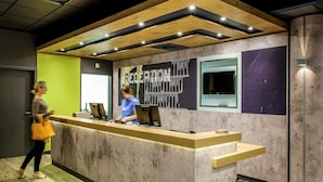 A reception desk with a modern design, a large window, and a wall with a chalkboard. - B&B Hotel Köln-porz (Cologne)