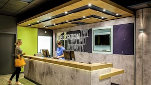 A reception desk with a modern design, a large window, and a wall with a chalkboard. - B&B Hotel Köln-porz (Cologne)