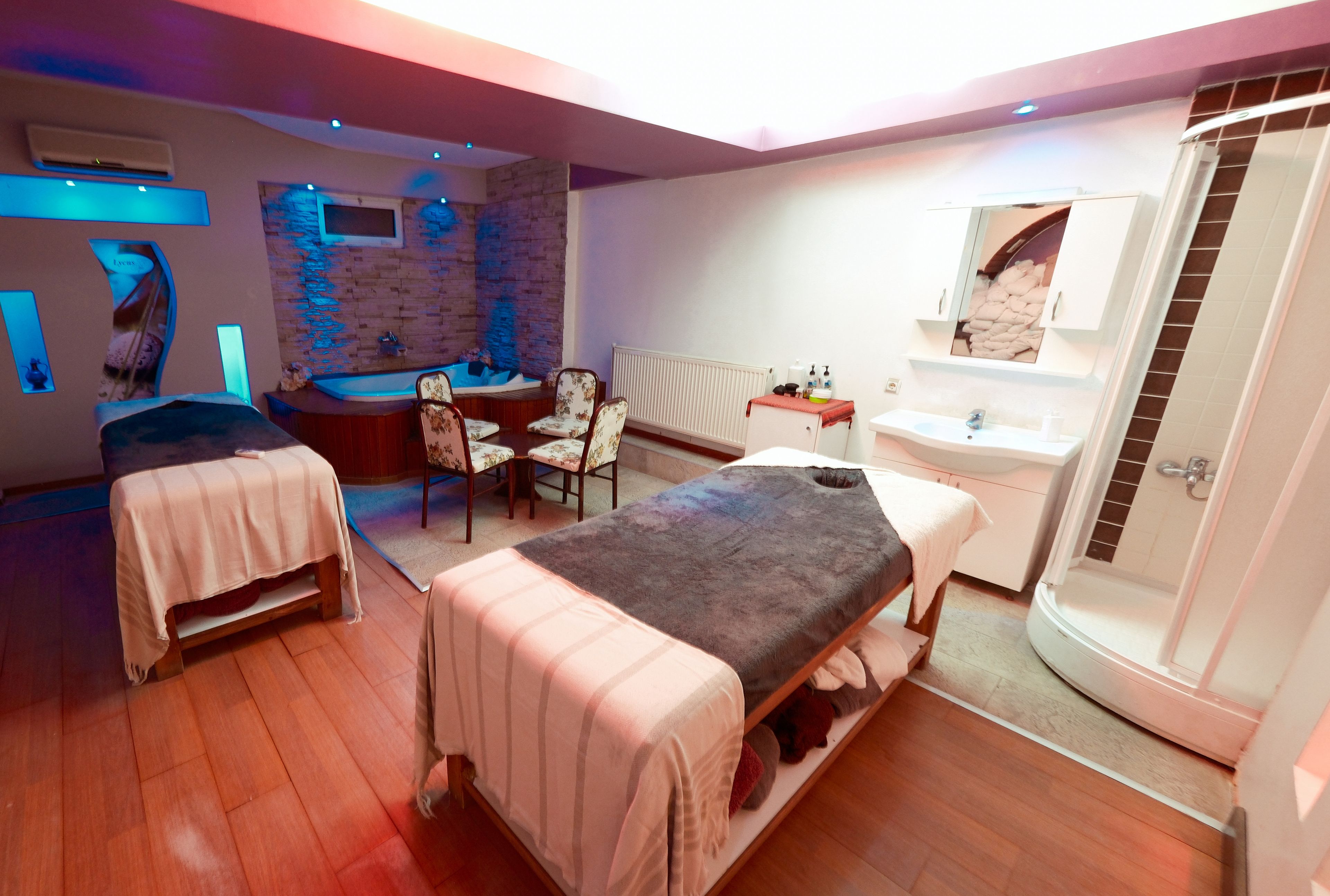 Quarto de hotel com duas camas, área de estar com cadeiras, banheira, mesa pequena e espelho.