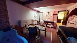A cozy room with a bed, a small table, two chairs, a radiator, and a wooden bench. - Lycus River Thermal Hotel (Denizli)