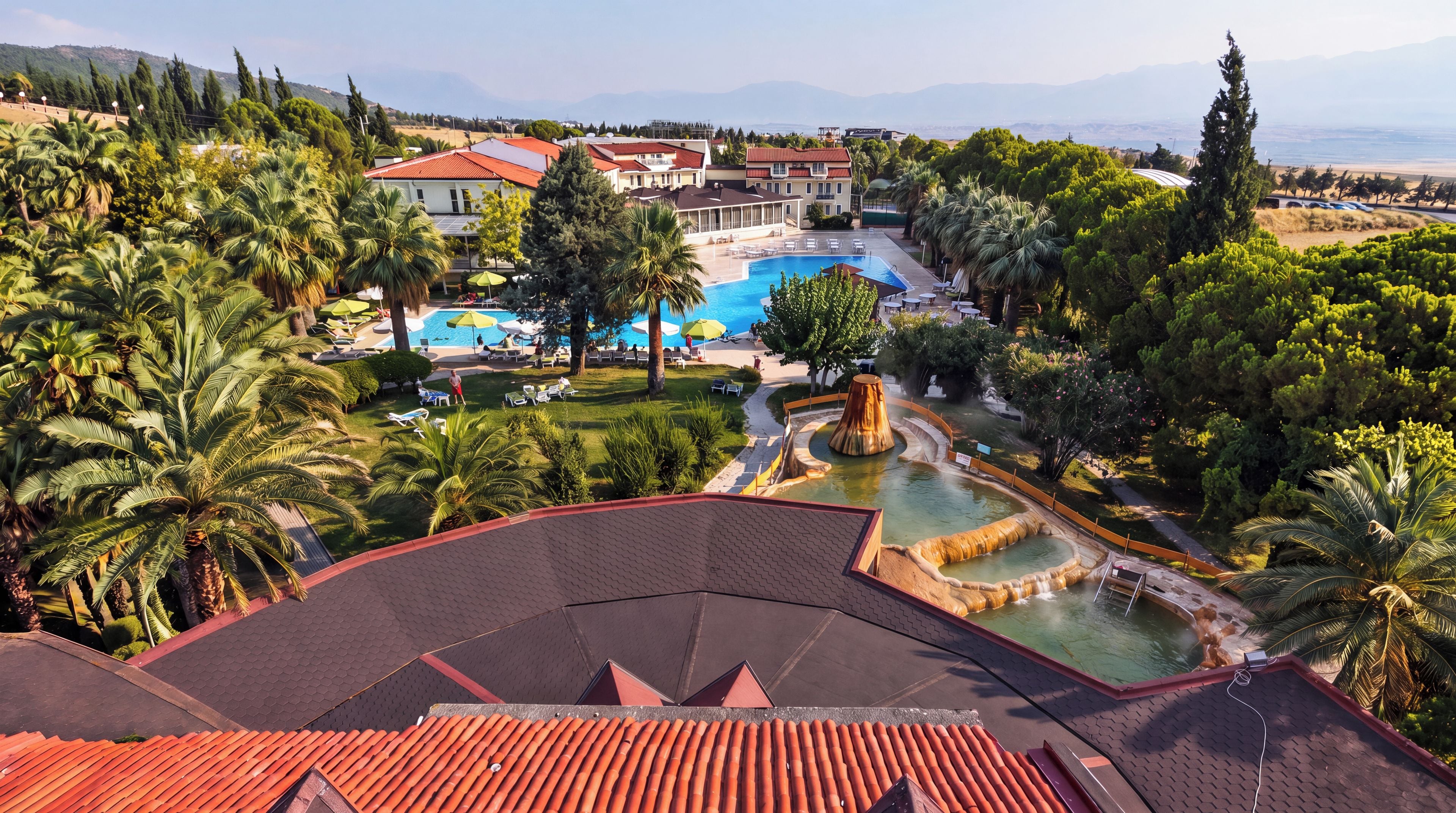 A resort with a swimming pool, palm trees, and a view of the mountains.