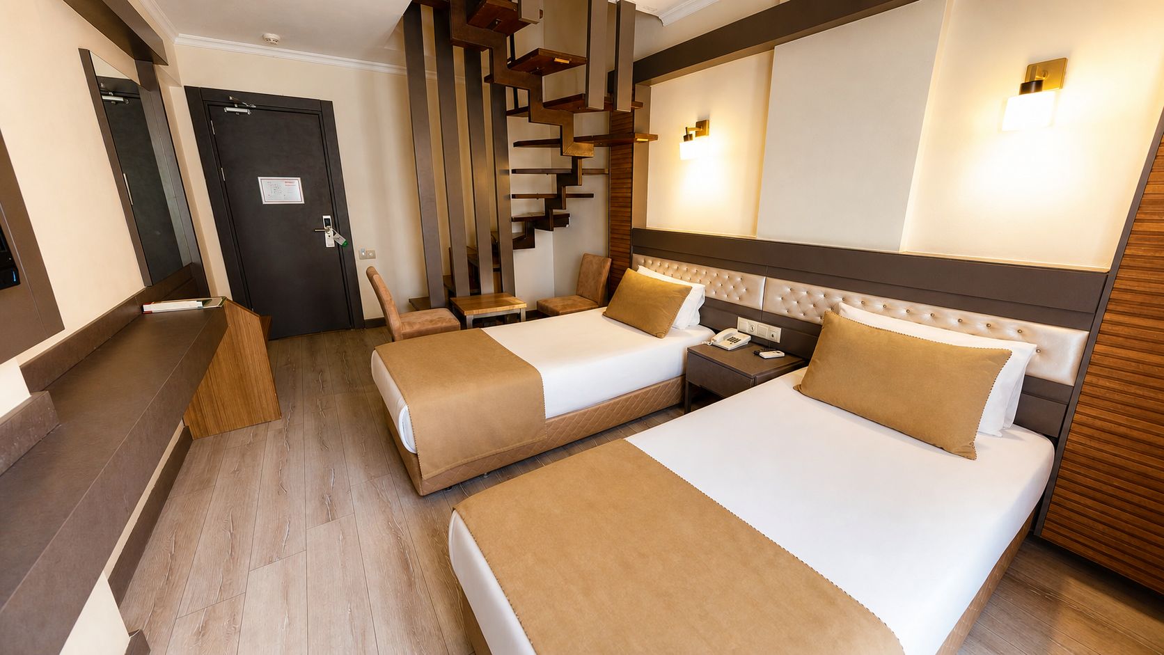 Habitación de hotel con dos camas, una escalera de madera, un escritorio y un teléfono en la mesita de noche.