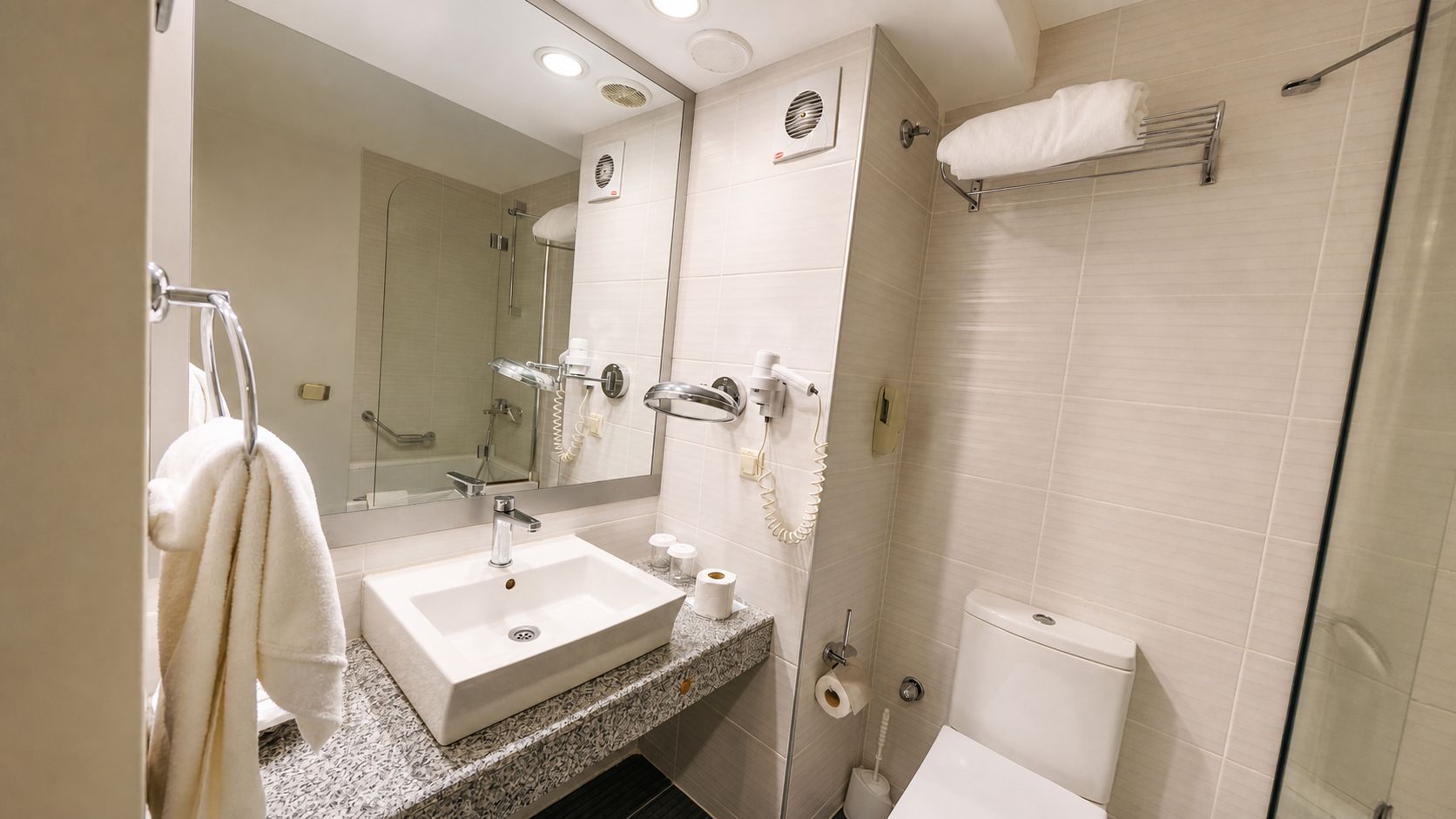 Un baño moderno con lavamanos, espejo, toallero y retrete.