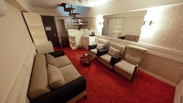 Una sala moderna con alfombra roja, una mesa de centro de vidrio y un conjunto de sofás.