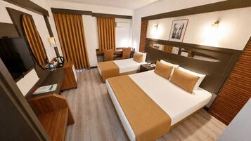 Quarto de hotel com duas camas, uma escrivaninha, televisão e banheiro.