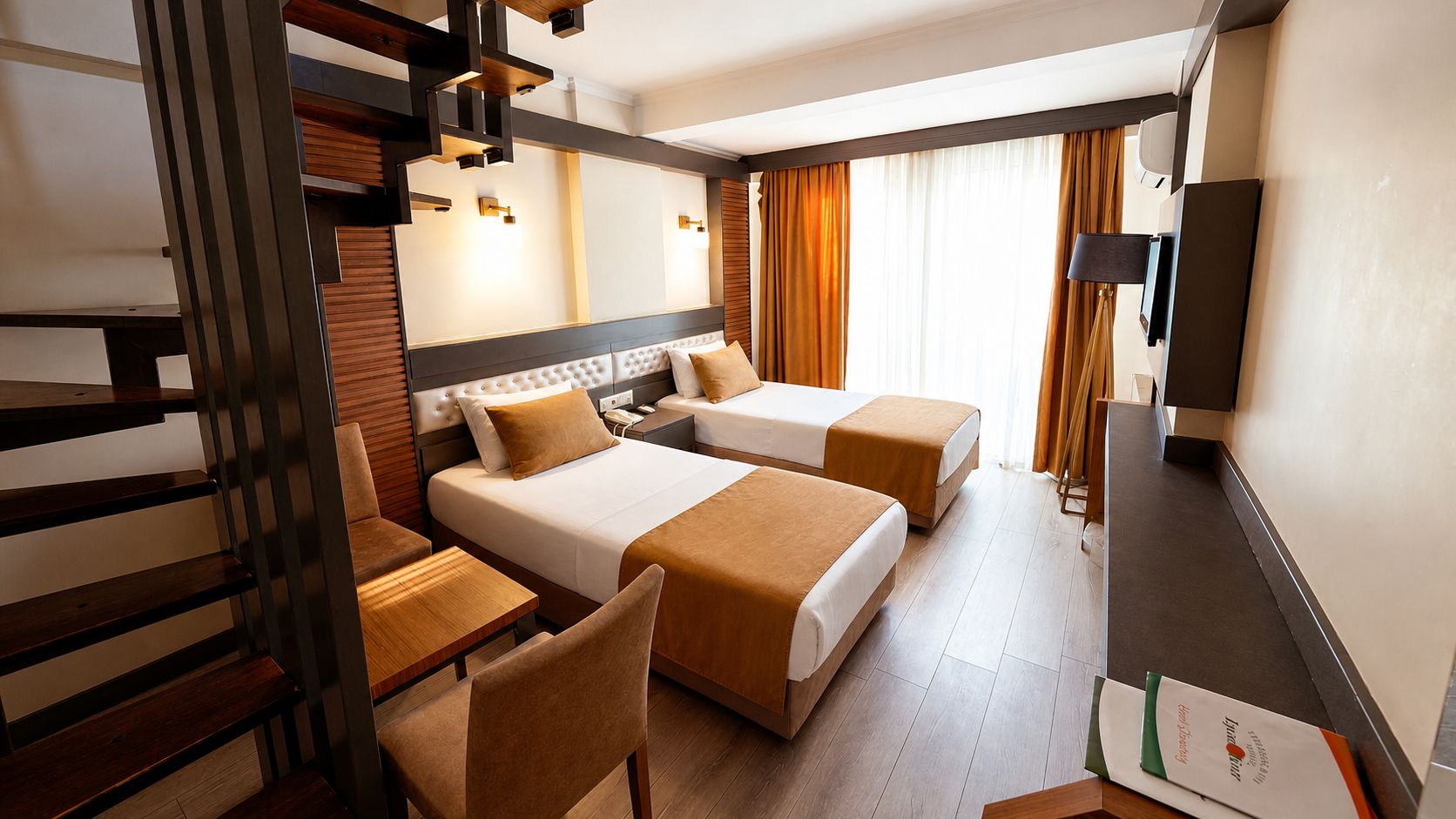Quarto de hotel com cama, escrivaninha, cadeira, televisão e janela com cortinas.