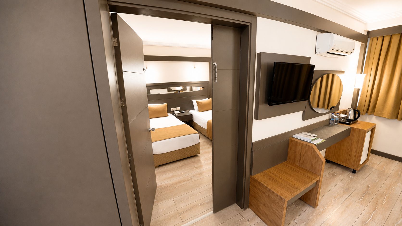 Habitación de hotel con cama, mesita de noche, escritorio con silla, televisor de pantalla plana montado en la pared y minibar.