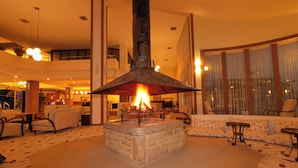 A lobby with a central stone fireplace, seating areas, and a large window with curtains. - Lycus River Thermal Hotel (Denizli)