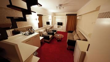 Una habitación de hotel con kitchenette, un sofá, una mesa de centro y un televisor.